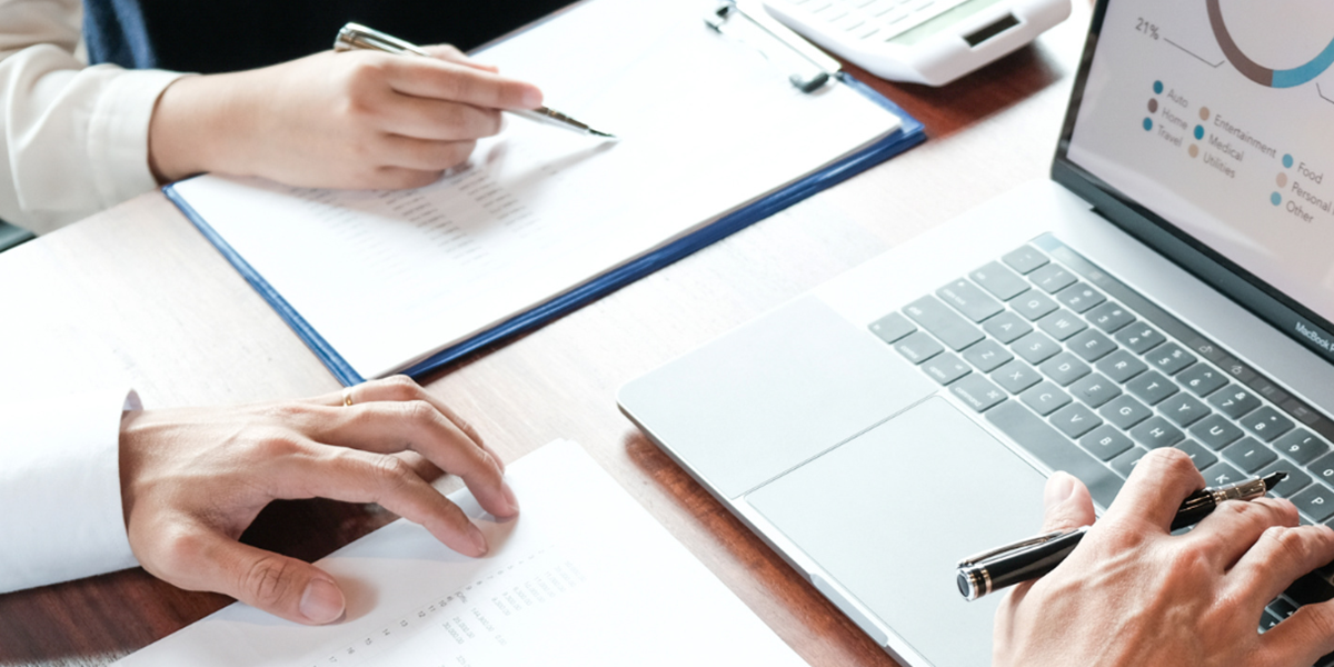 People sitting at a desk with a laptop taking notes